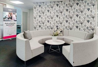 Circular white sofa area for informal meetings in front of a tree-patterned wall.