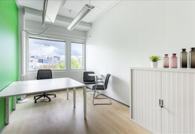 Bright private office featuring a green accent wall and a white desk with views.