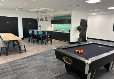 Communal breakroom with a pool table, kitchenette, and high-top seating.