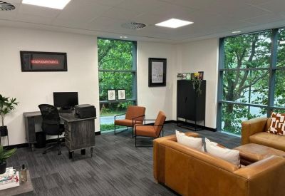 Private office suite with a wooden desk, task chair, and leather armchairs.
