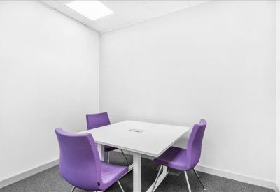 Small breakout room with a square table and vibrant purple chairs.