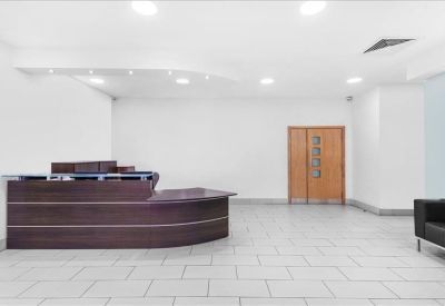 Spacious reception area with a dark wood front desk and white tiled floor.