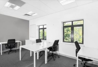 Bright office space with white desks and black ergonomic chairs.