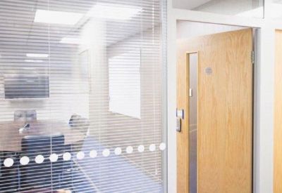 Glass-walled meeting room with venetian blinds and a round table.