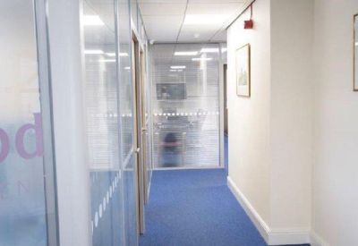 Modern office corridor with blue carpet and glass partitions.