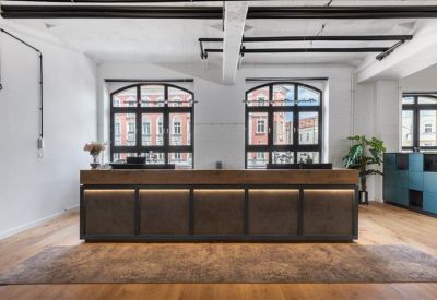 Large wooden reception desk with warm backlighting and arched windows.