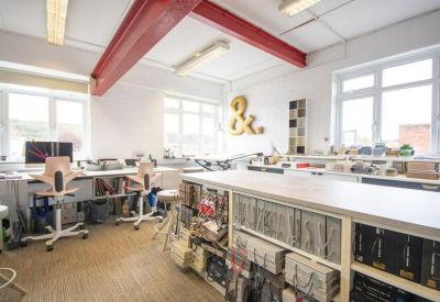 Spacious workshop area with a large central island, red steel beams, and wood flooring.