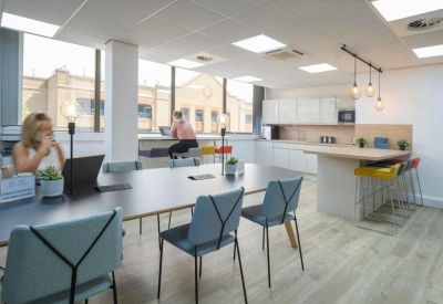 Open-plan communal kitchen and break area with modern dining island and bar stools.