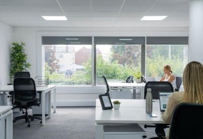 Bright private office suite with large windows and minimalist white desks.