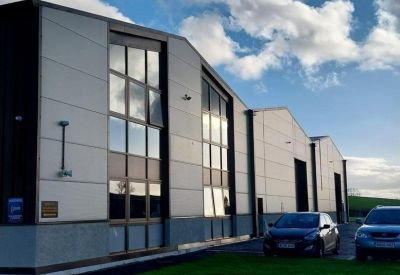 Contemporary office building exterior with white paneling and tall windows under a bright sky.