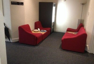 Small waiting area featuring three red armchairs and a vending machine.