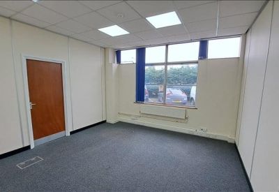 Private office suite with grey carpet, wooden door, and large window providing natural light.