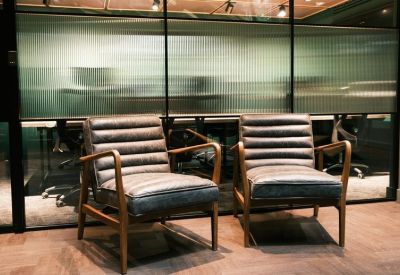 Two stylish ribbed leather armchairs in a lobby area with frosted glass partitions.