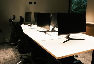 Modern workspace featuring white desks with multiple monitors and ergonomic chairs.