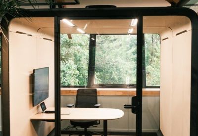 Private glass-walled meeting pod with a desk, chair, and large monitor.