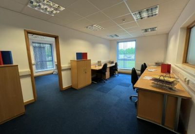 Bright multi-desk office space with blue carpeting and large windows.
