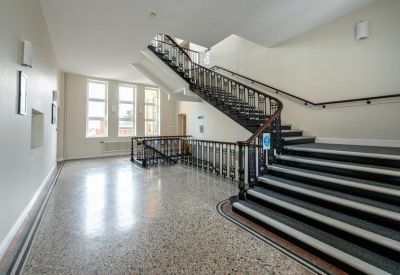 Spacious communal landing with a sweeping dark wood staircase and bright windows.