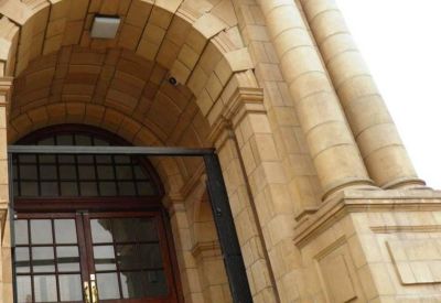 Grand stone arched entrance with tall columns and wooden double doors.