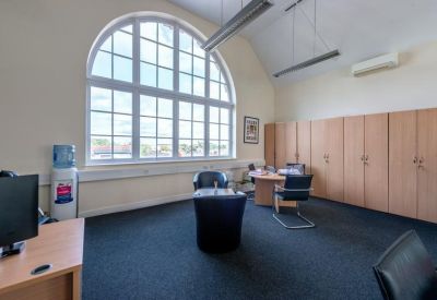 Private office suite featuring a large arched window and integrated storage cabinets.