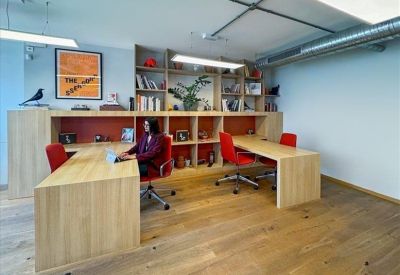 Coworking space with long wooden desks, ergonomic chairs, and modern lighting.