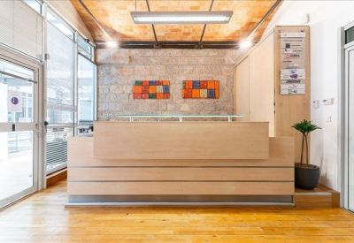 Minimalist wooden reception desk in a lobby with exposed stone walls and warm lighting.