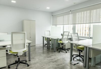 Bright open-plan workspace with multiple white desks and lime green ergonomic chairs.