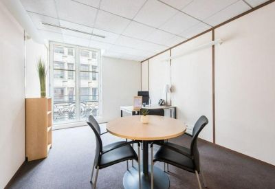 Private four-person office with a round meeting table, desk, and large window.