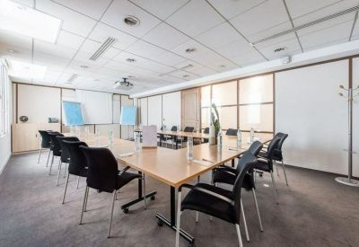 Professional meeting room featuring a U-shaped wooden table and black ergonomic chairs.