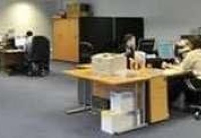 Spacious open-plan office with multiple workstations and staff members working at desks.