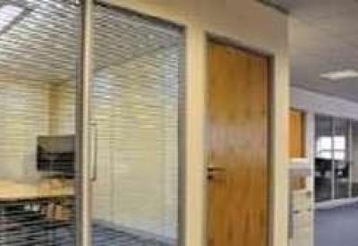 Bright conference room with a large wooden table and glass partitions with blinds.