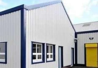 Modern industrial building unit with white cladding and a yellow roller shutter door.