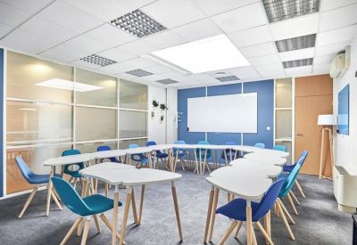 Meeting room with white curved tables arranged in a horseshoe shape and vibrant blue chairs.