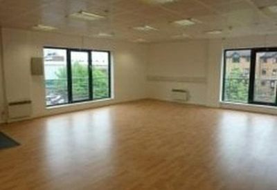 Bright, empty office suite with wood floors and large windows overlooking the street.