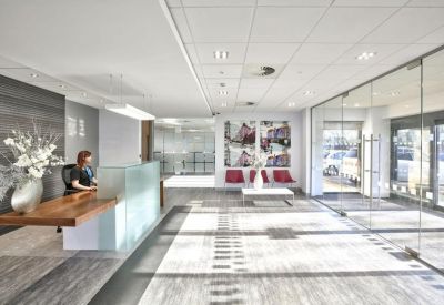 Bright reception area with a wood-top front desk, seating area, and glass partitions.
