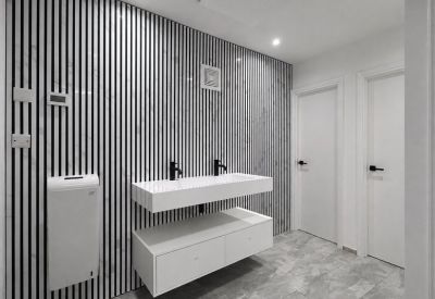 Modern restroom with a white double vanity, black fixtures, and a monochrome slatted feature wall.