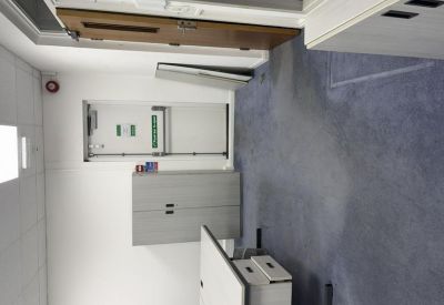 Office corridor featuring storage cabinets and a doorway leading to workspace areas.