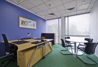 Private office with blue feature wall, wood-finish desk, and small meeting table.