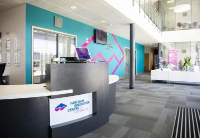 Bright reception area with a teal feature wall, modern black desk, and mezzanine level.