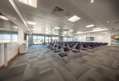 Spacious auditorium-style meeting room with rows of purple chairs and grey carpet.