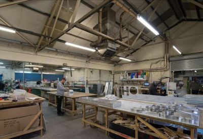 Large workshop area with industrial workbenches and overhead ventilation system.