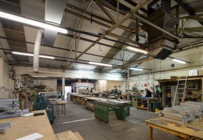 Spacious industrial workshop with green machinery and bright overhead lighting.