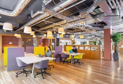 Spacious open-plan workspace with purple and yellow dividers and industrial-style ceiling.
