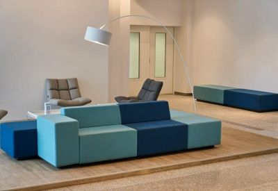 Modern lobby area featuring a geometric blue and teal modular sofa and a sleek arched floor lamp.