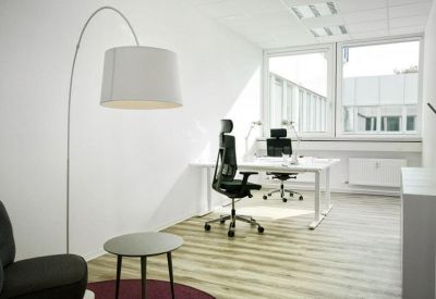 Private office suite featuring a white desk, ergonomic chair, and a large arched lamp over a side table.