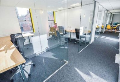 Private office suites separated by glass partitions with ergonomic chairs and natural light.