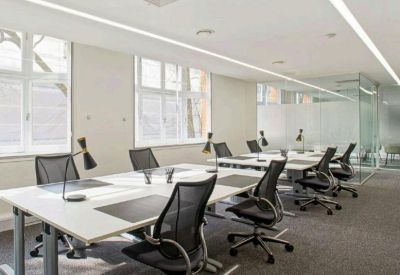 Bright open-plan office with white desks, ergonomic black chairs, and large windows.