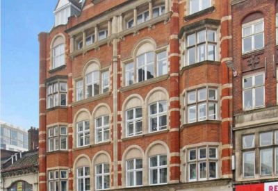 Grand red brick Victorian exterior of the Fleet Street office building with stone archways and storefronts.