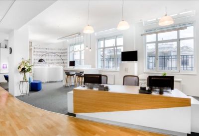 Spacious reception area with a wood-fronted desk, pendant lighting, and lounge seating.