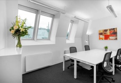 Bright private office suite featuring a white table, black chairs, and slanted attic windows.