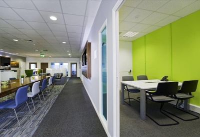 Bright coworking area with a long wooden table, blue chairs, and a lime green feature wall.
